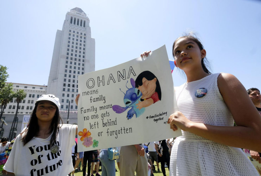 A little girl holds a sign reading